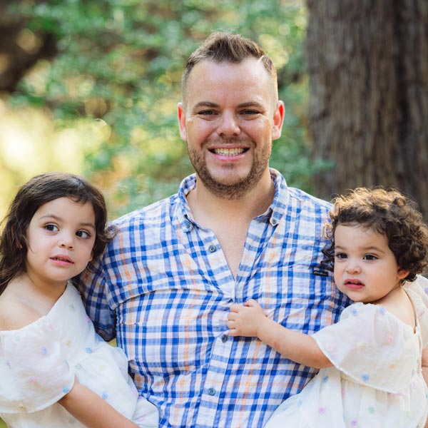Dr. Christopher DeMarco smiling with two young daughters in Dripping Springs, TX