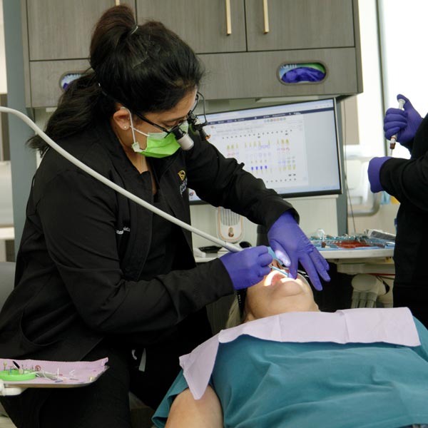 A dentist is using a tool on a patient in black scrubs in Dripping Springs, TX